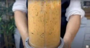 Blending vegetables for a homemade sauce in a kitchen blender.